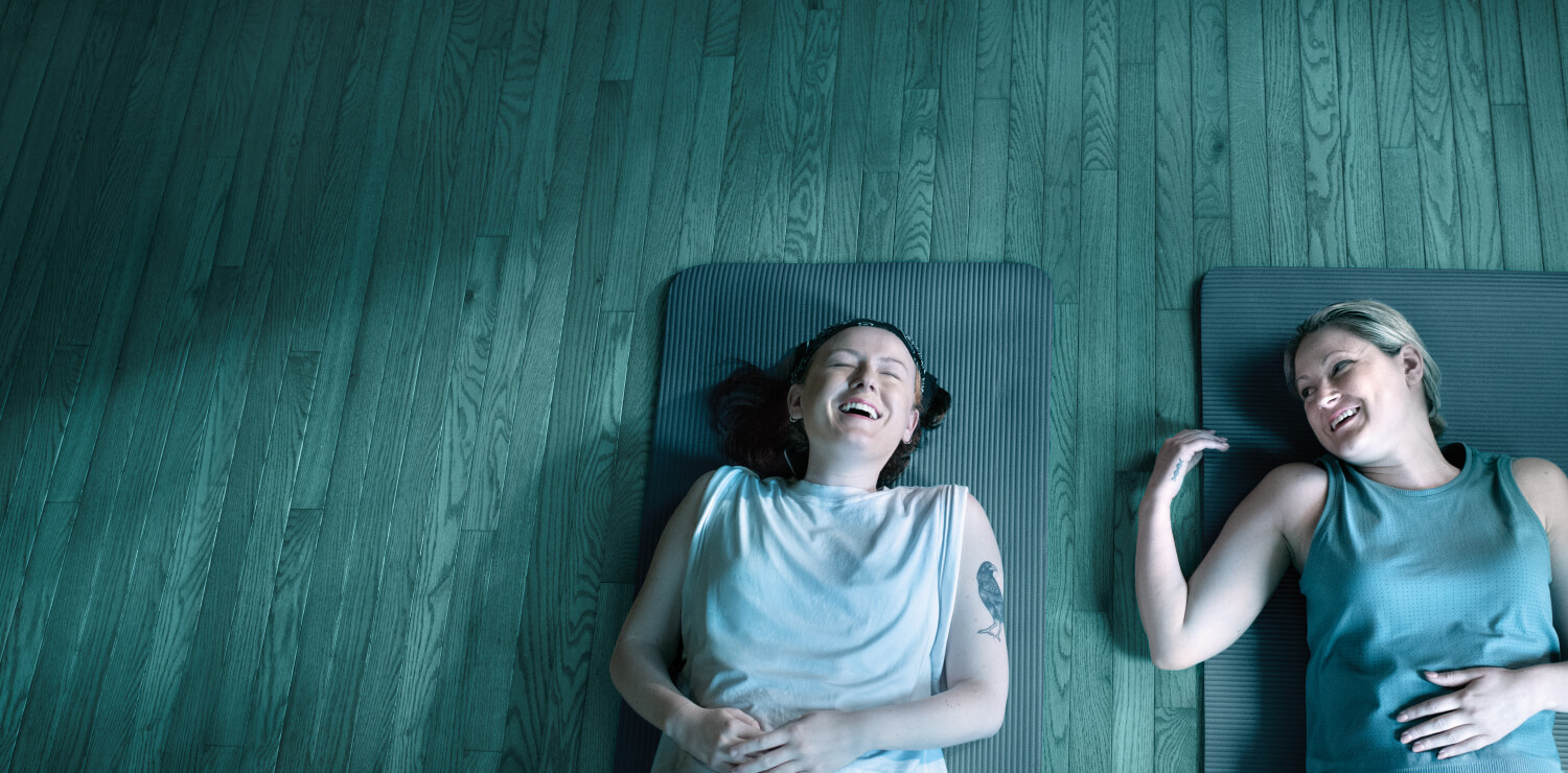 Ambassadors Maddie and Emma lying on yoga mats, laughing-image